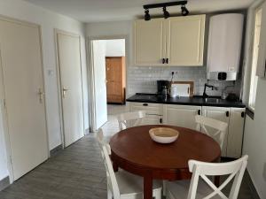 a kitchen with a wooden table and white chairs at Balatonszemes small House in Balatonszemes