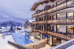een gebouw met een zwembad en een resort bij Hotel habicher hof 4-Sterne-Superior in Oetz +55 foto's