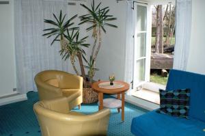 a living room with chairs and a table and palm trees at Fewo Fischotter in Lehde