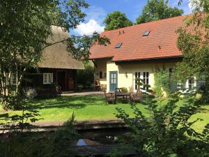 a house with a red roof and a yard at Fewo Fischotter in Lehde