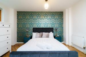 a bedroom with a large bed with blue wallpaper at Modern two bedroom two bath opp tube station (central line) in London