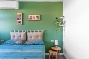 1 dormitorio con 1 cama con pared verde en PM Via Gabriele D' Annunzio Guest House en Pero