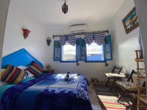 a bedroom with a bed with a blue comforter and windows at Riad sakura in Chefchaouen