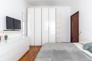 a white bedroom with a bed and a tv at Pane&Pomodoro Apartment in Bari