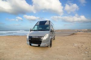una furgoneta plateada estacionada en una playa cerca del océano en Camper Van - Encuentra tu camino, en Marzagán