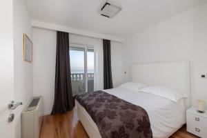a bedroom with a bed and a large window at Villa 3M in Tučepi