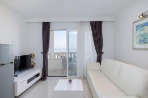 a living room with a white couch and a television at Villa 3M in Tučepi