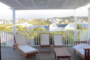 スティル・ベイにあるPlankeplekkieの椅子3脚、ベッド1台、テーブル1台のあるポーチ