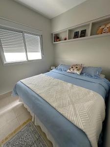 a bedroom with a bed with blue sheets and a window at Maravilhoso Apartamento inteiro em frente HIAE e Estadio Morumbi in São Paulo