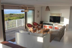 スティル・ベイにあるPlankeplekkieのソファと椅子、バルコニーのあるリビングルーム