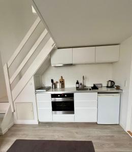 uma cozinha com armários brancos e um fogão em Small cosy appartment em Skanderborg