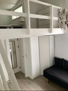 uma cama alta branca com um sofá preto num quarto em Small cosy appartment em Skanderborg