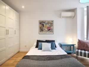 um quarto branco com uma cama com almofadas azuis em My City Home - Fantastic apartament at Moncloa for students em Madrid