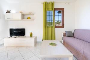a living room with a purple couch and a tv at Angel Village in San Teodoro