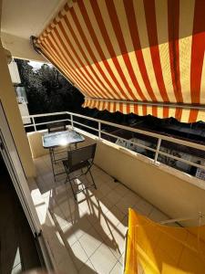 a balcony with a table and a striped umbrella at Appartement centre Arcachon in Arcachon