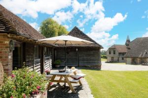 a patio with a table and an umbrella at Bull Pen and Cart Lodge in Herstmonceux
