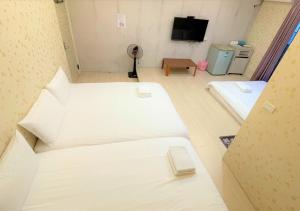a room with two beds and a flat screen tv at 逢甲福舍 in Hsia-shih-pi