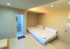 a bedroom with two beds and a bathroom at 逢甲馨宿 in Hsia-shih-pi