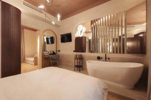 ein Schlafzimmer mit einem großen weißen Bett und einer Badewanne in der Unterkunft Zenith Premium Suites in Thessaloniki