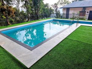 a swimming pool in a yard with green grass at Peakaavu Cottages in Idukki