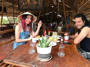 un homme et une femme assis à une table dans l'établissement Maison en Bambou Phong-Le Vent, à Sa Ðéc