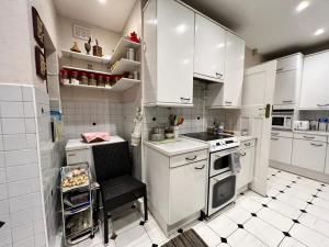 a kitchen with white cabinets and a chair in it at LiveStay Room with Free Parking in Wembley in London