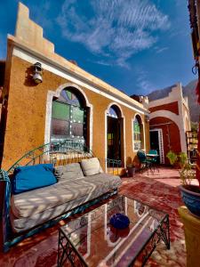 eine Couch auf einer Terrasse mit einem Glastisch in der Unterkunft La Maison Traditionnelle Hôtel et guesthouse in Tafraout