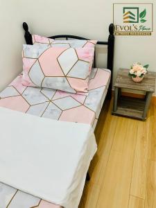 - un lit avec des oreillers roses et blancs et une table dans l'établissement Trees Residences Staycation 1br/2br, à Manille