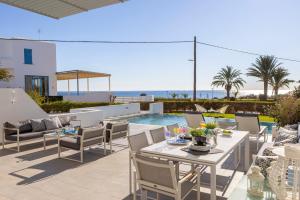 a patio with a table and chairs and a pool at Protaras Elaia Luxury Seafront Villa in Protaras