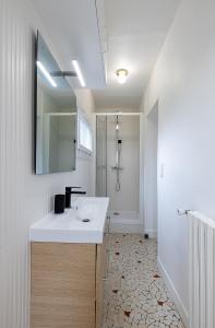a bathroom with a white sink and a mirror at Smart Inn Fontainebleau Centre- Appartement 1 chambre in Fontainebleau