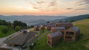 a group of buildings on a hill with mountains in the background at Peterhof Chalets in Batschuns