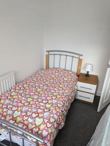 a bedroom with a bed and a nightstand with a bedspread with hearts at Above us only sky in Kirkby