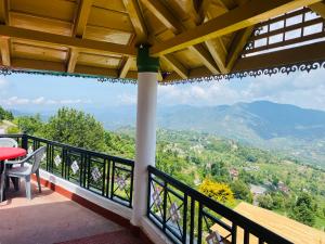 un balcón con una mesa y vistas a las montañas en Sunstone House, en Mukteshwar
