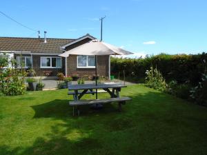 uma mesa de piquenique com um guarda-chuva no quintal em Immaculate 2 bedroom bungalow close to beaches em Pendine