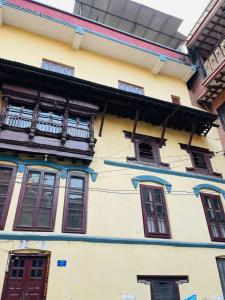 Edificio amarillo con ventanas y balcón en Heranya Hostel en Katmandú