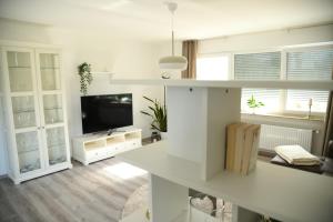 een witte woonkamer met een televisie en een tafel bij Ferienwohnung Niestetal in Niestetal