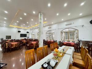 a restaurant with tables and chairs in a room at Cat Ba Plaza Hotel in Cat Ba