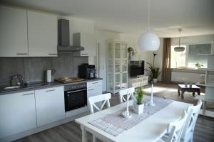 een keuken met witte kasten en een tafel met stoelen bij Ferienwohnung Niestetal in Niestetal