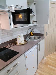 a kitchen with a sink and a microwave at SureBillionaire Home Deluxe Queen Studio in London
