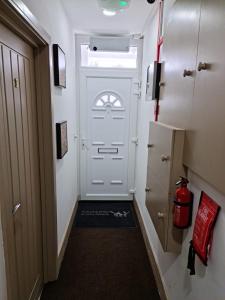 um corredor com uma porta branca e um frigorífico em SureBillionaire Home Deluxe Queen Studio em Londres
