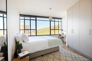 a bedroom with a large bed with a large window at City Style with Striking Views in Cape Town