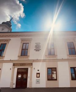 Biały budynek ze słońcem świecącym na niebie w obiekcie Kounický dvůr w mieście Dolní Kounice