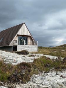 a small house on a beach with a field at Kylesku Lodges in Kylestrome