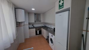 a small kitchen with white cabinets and a washer and dryer at Moderno Apartamento 3 dormitorios, garaje y piscina in La Algaba