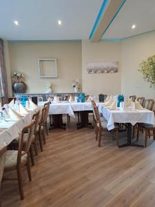 uma sala de jantar com mesas brancas e cadeiras de madeira em Hotel Deutsches Haus em Lampertheim