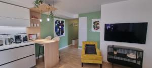 a living room with a kitchen with a tv on the wall at Sur un Nuage by Plaza in Serris