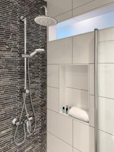 a shower in a bathroom with white tiles at Modern und Gemütlich Augsburg Center Kongress in Augsburg