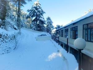 a yard covered in snow next to a building at Surya Resort Dalhousie in Dalhousie