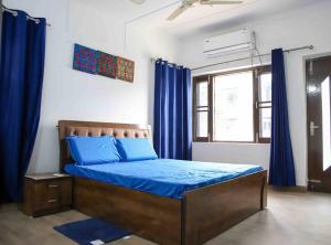 a bedroom with a bed with blue sheets and blue curtains at 3BR Apartment by B-Town stays in Dehradun