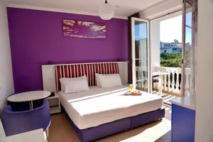 1 dormitorio con cama y pared púrpura en Hotel Monaco & Garden, en Golem